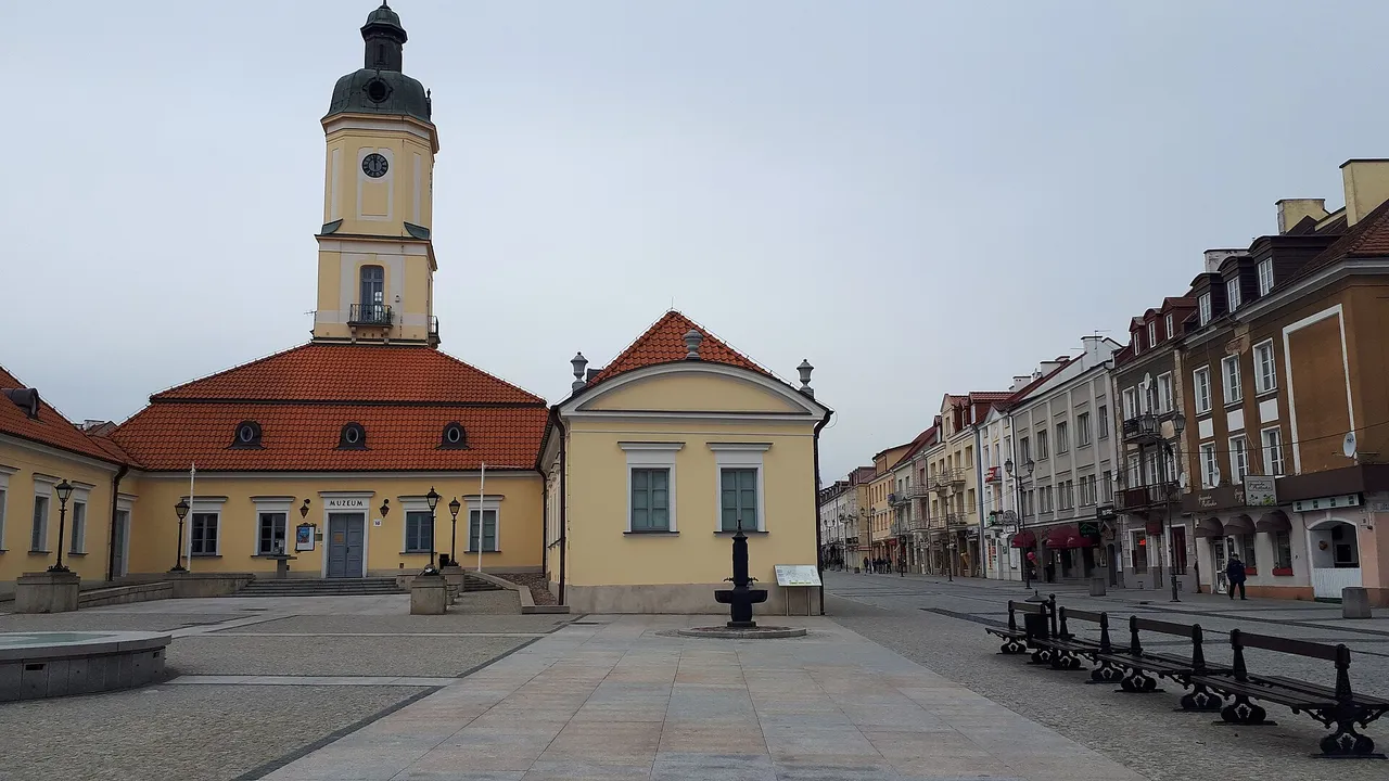 Balstogės Kosciuškos aikštė su geltonu rotušės bokštu ir raudonu čerpių stogu apsiniaukusią dieną