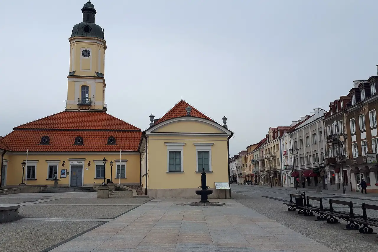 Balstogės Kosciuškos aikštė su geltonu rotušės bokštu ir raudonu čerpių stogu apsiniaukusią dieną