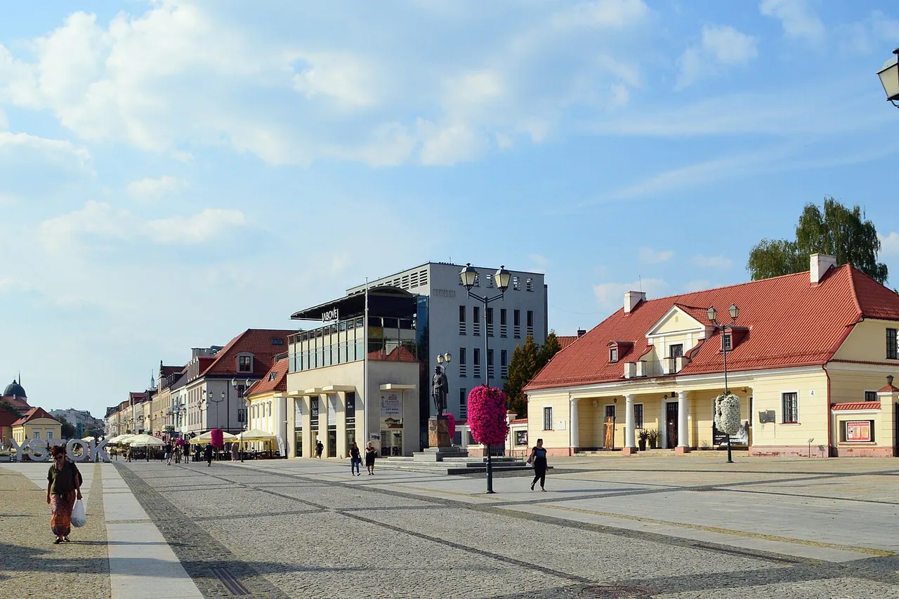 Balstogės Kosciuškos aikštė su Rotušės bokštu tolumoje ir žydinčiais krepšiais