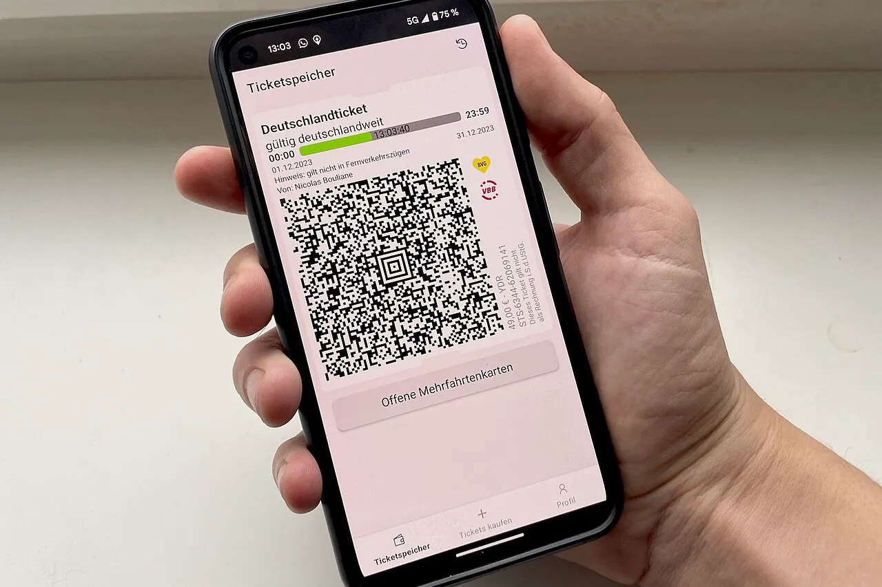 Ranka laiko telefoną, kurio ekrane rodomas bilietas su dideliu QR kodu