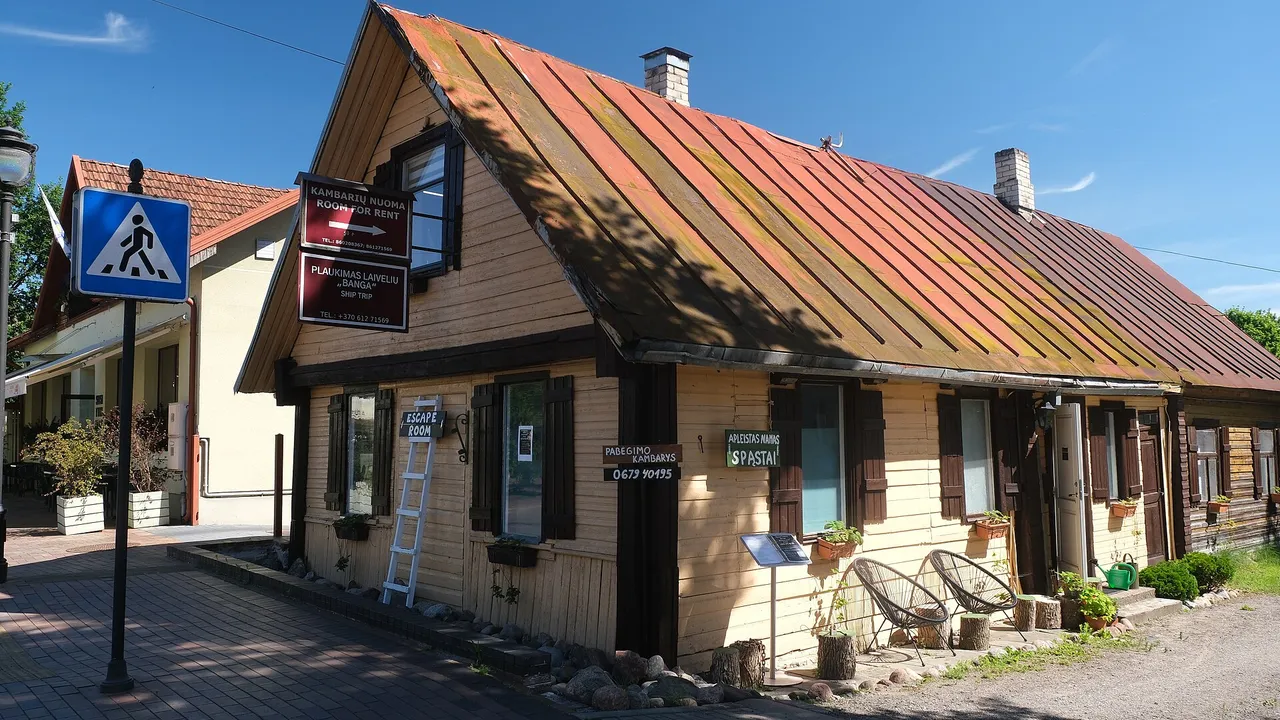 Medinis geltonas namas su oranžiniu stogu Birštone, priekyje – grindinio gatvė