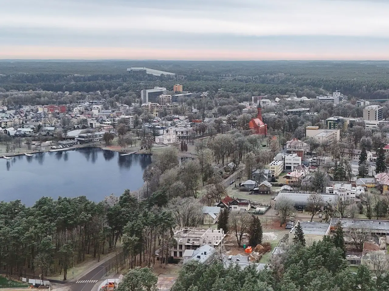 Druskininkų ežeras ir miesto stogai su raudonos plytos bažnyčia rudens rytą, iš oro