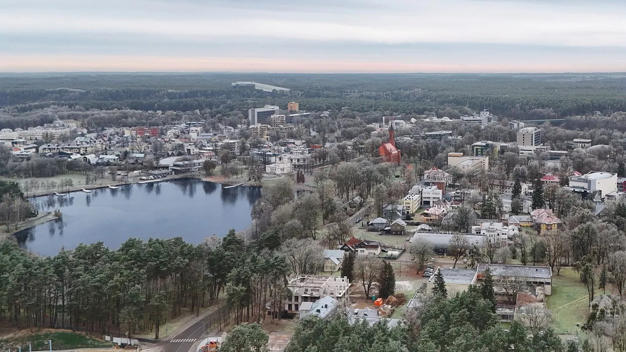 Druskininkų ežeras ir miesto stogai su raudonos plytos bažnyčia rudens rytą, iš oro