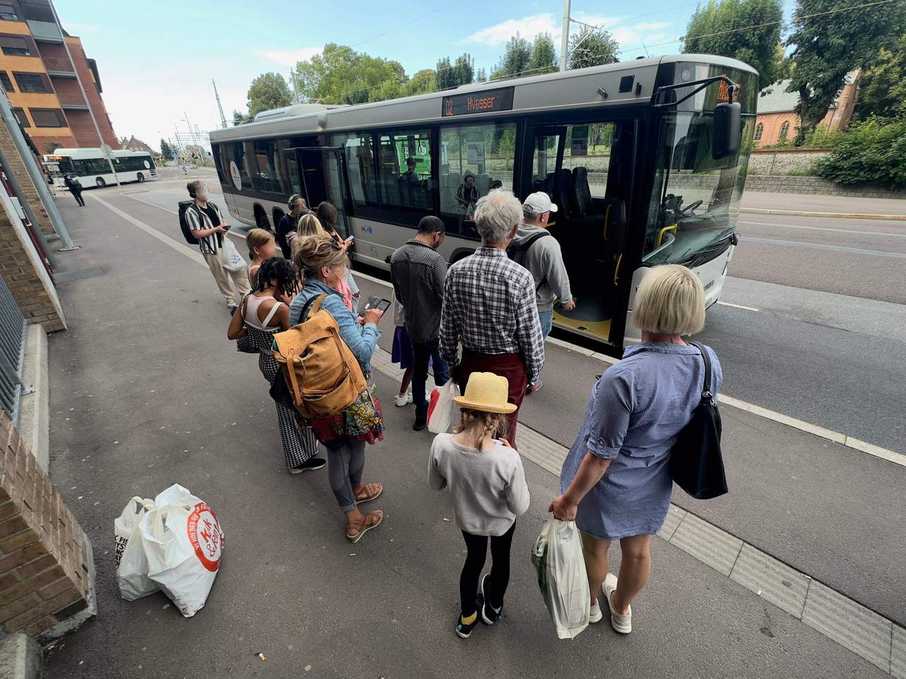 Keleiviai stotelėje prieš lipdami į autobusą tikrina bilietus savo išmaniuosiuose telefonuose