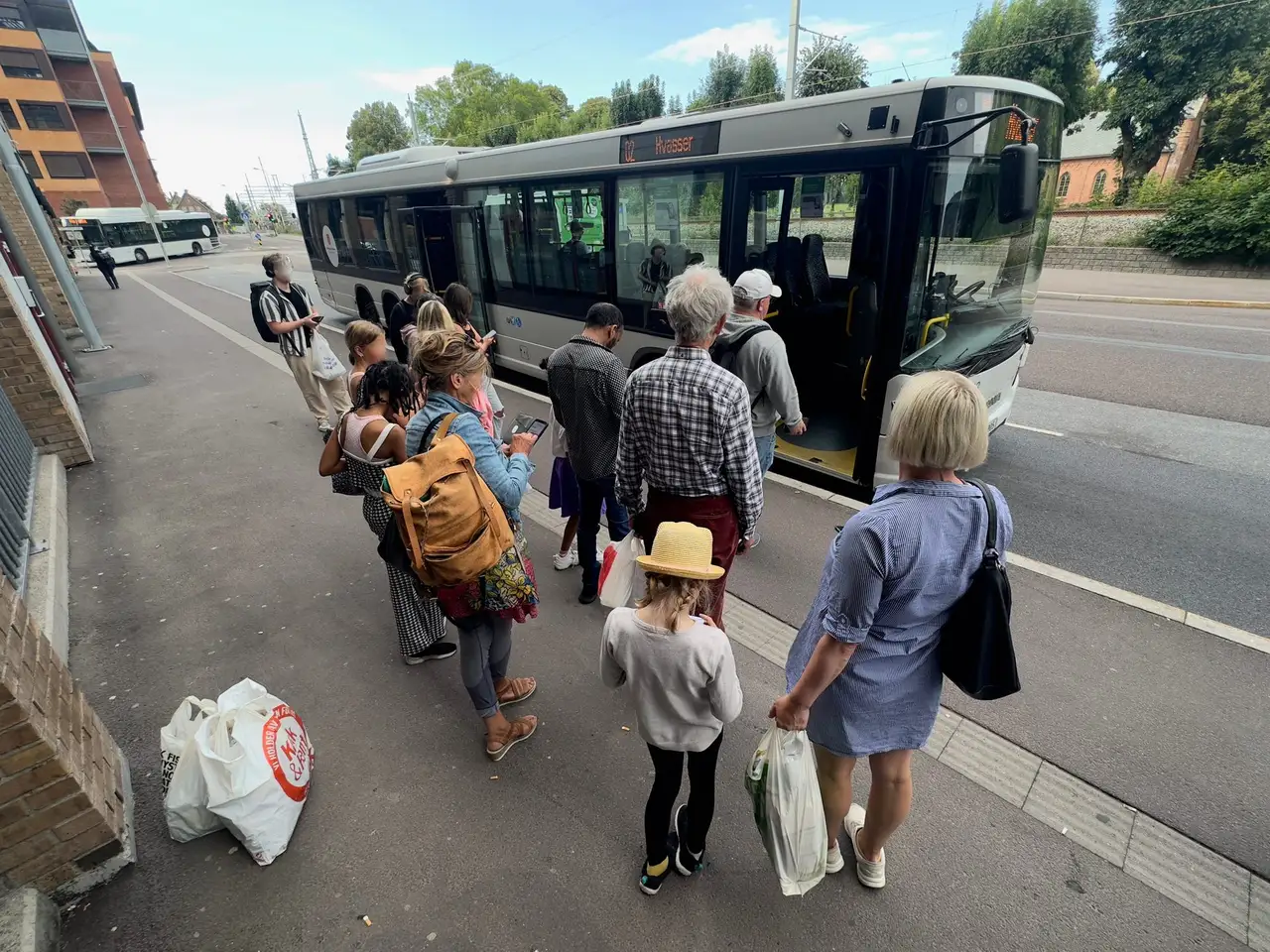 Keleiviai stotelėje prieš lipdami į autobusą tikrina bilietus savo išmaniuosiuose telefonuose