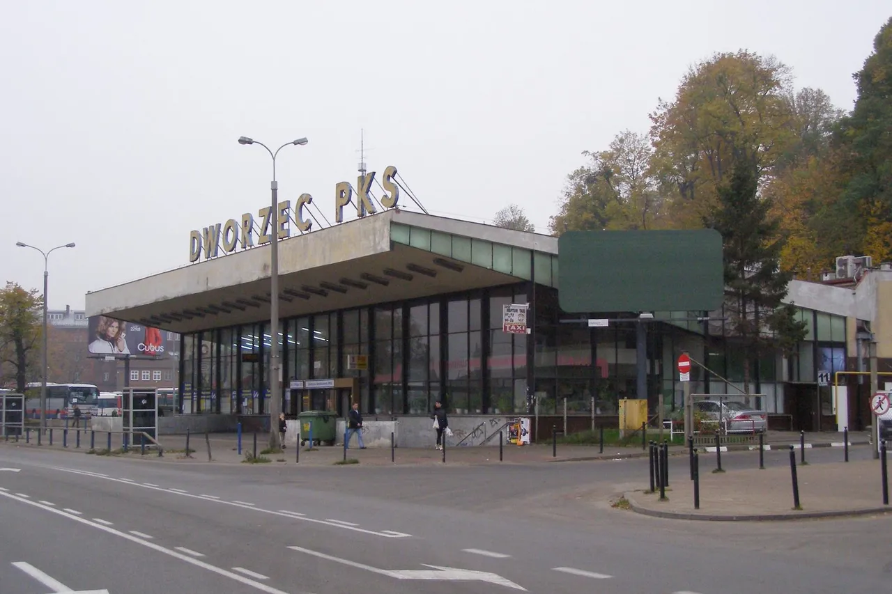 Gdansko autobusų stoties pastatas su dideliu užrašu virš plokščio stogo ir medžiais už pastato
