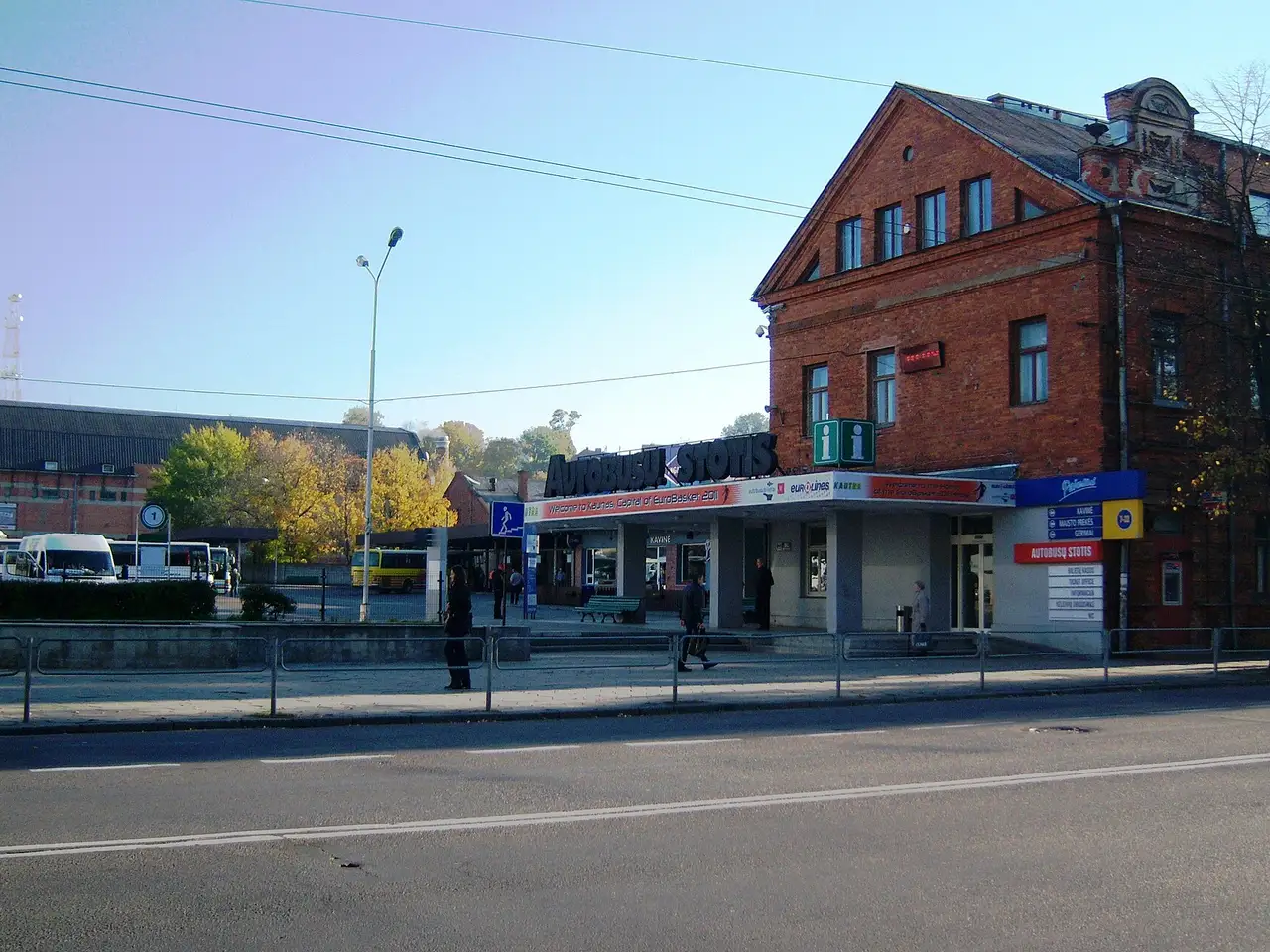 Raudonų plytų Kauno autobusų stoties pastatas su užrašu „Autobusų stotis“ ir stovintys autobusai