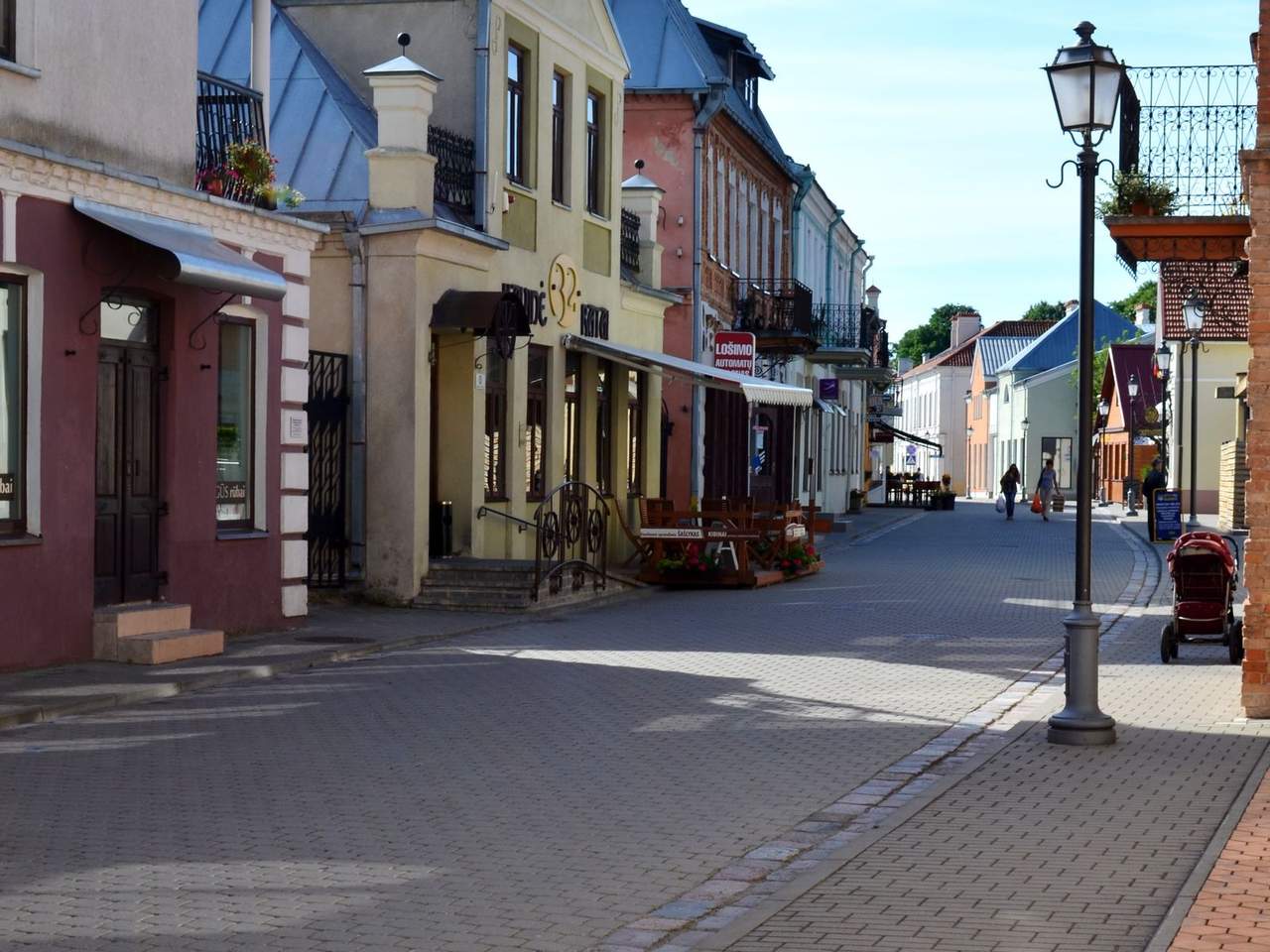 Pėsčiųjų gatvė Kėdainių senamiestyje su spalvingais namais ir gatvės žibintu