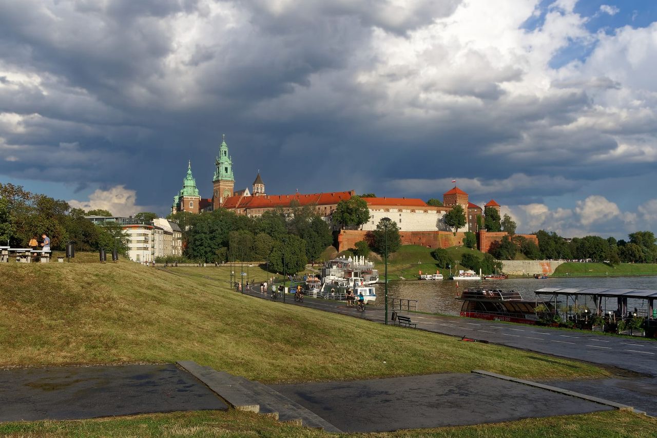 Vavelio pilis ant kalvos virš Vyslos, priekyje žolėta pakrantė po audringu dangumi
