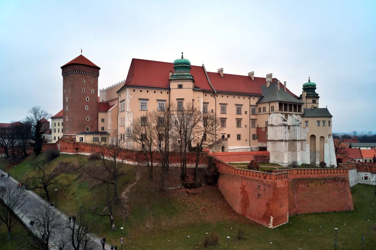 Vavelio pilies bokštai ir raudonos plytos sienos virš žalios kalvos Krokuvoje
