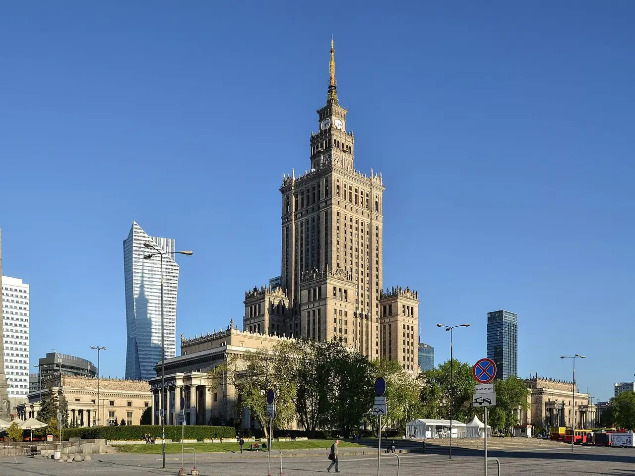 Kultūros ir mokslo rūmų bokštas su laikrodžiu tarp šiuolaikinių dangoraižių giedrą dieną