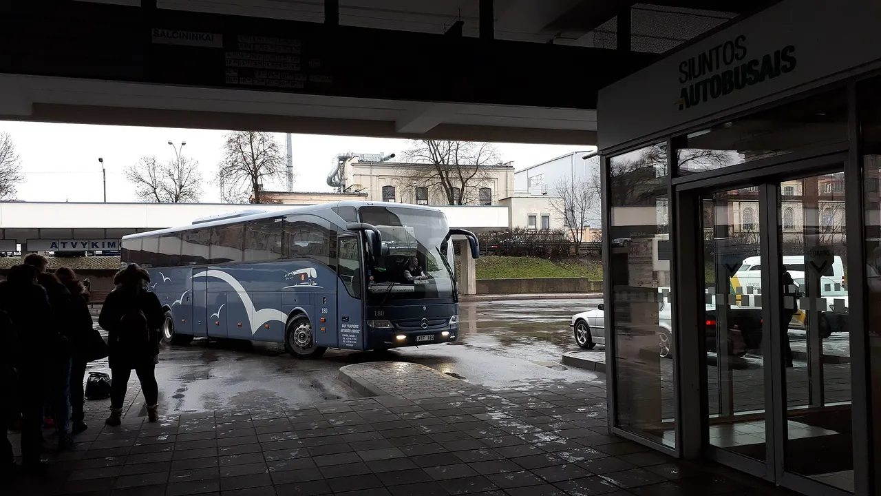 Tarpmiestinis autobusas atvažiuoja prie Vilniaus autobusų stoties perono lietingą dieną
