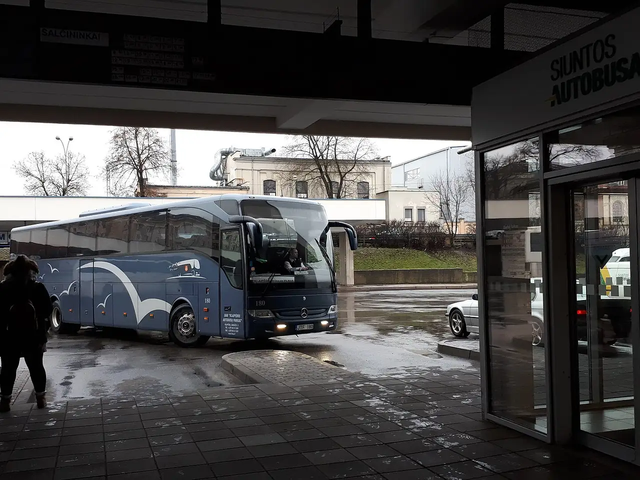 Tarpmiestinis autobusas atvažiuoja prie Vilniaus autobusų stoties perono lietingą dieną