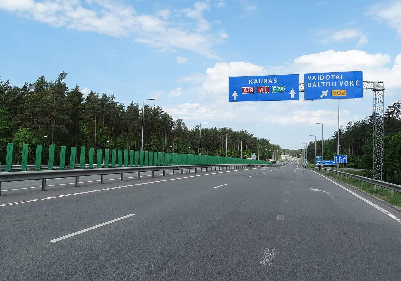 Tuščias greitkelis A19 su mėlynu ženklu į Kauną tarp pušynų Vilniaus apylinkėse