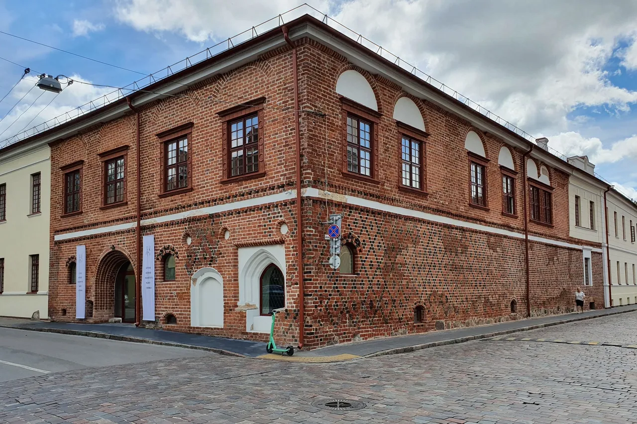 Raudonų plytų pastatas Kauno senamiestyje, matomas nuo gatvės kampo, grįsta gatvė
