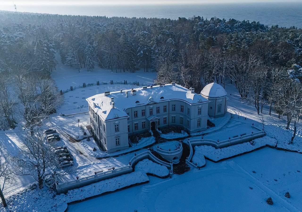 Sniegu padengti Tiškevičių rūmai su Palangos gintaro muziejumi, aplink pušys ir jūra horizonte