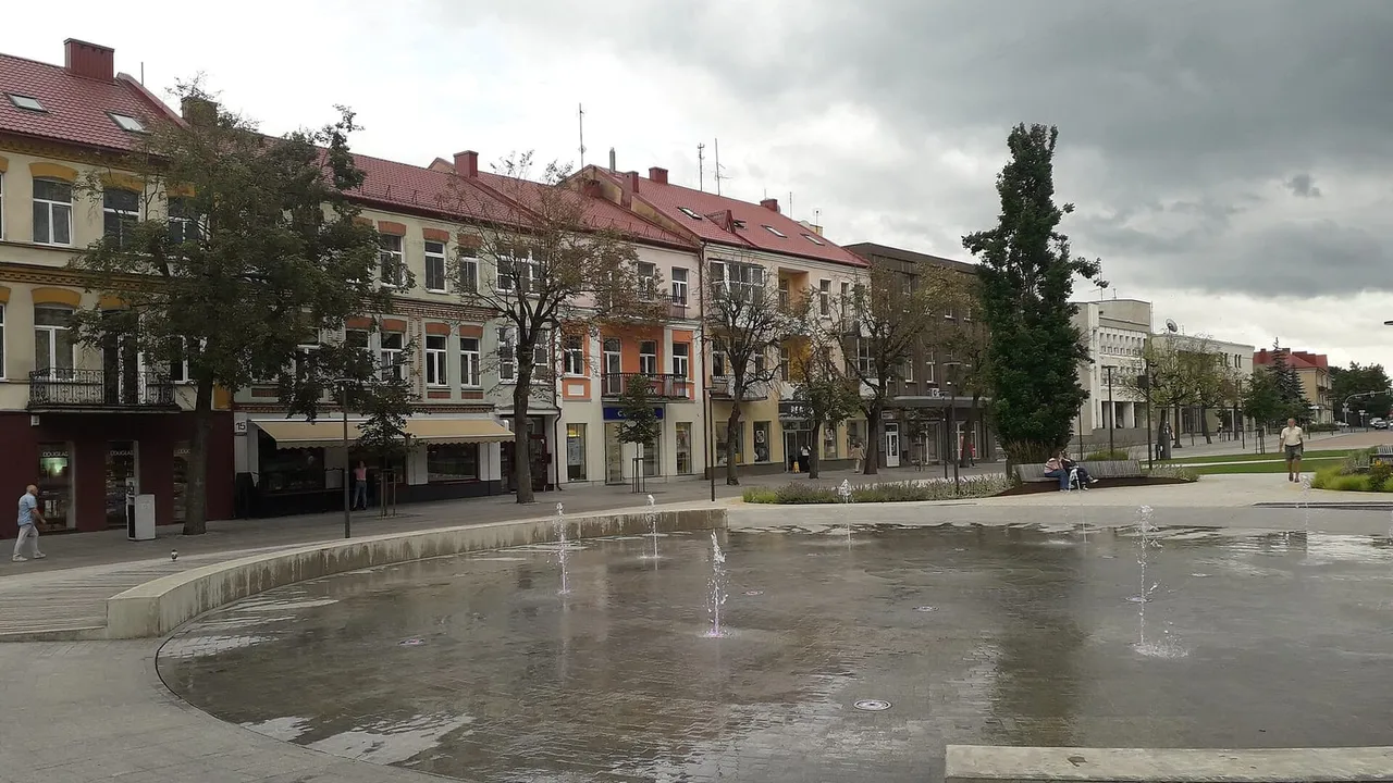 Laisvės aikštės fontano baseinas Panevėžyje ir apie jį išsirikiavę spalvoti dviaukščiai pastatai