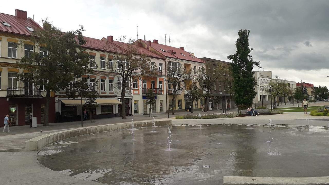 Laisvės aikštės fontano baseinas Panevėžyje ir apie jį išsirikiavę spalvoti dviaukščiai pastatai