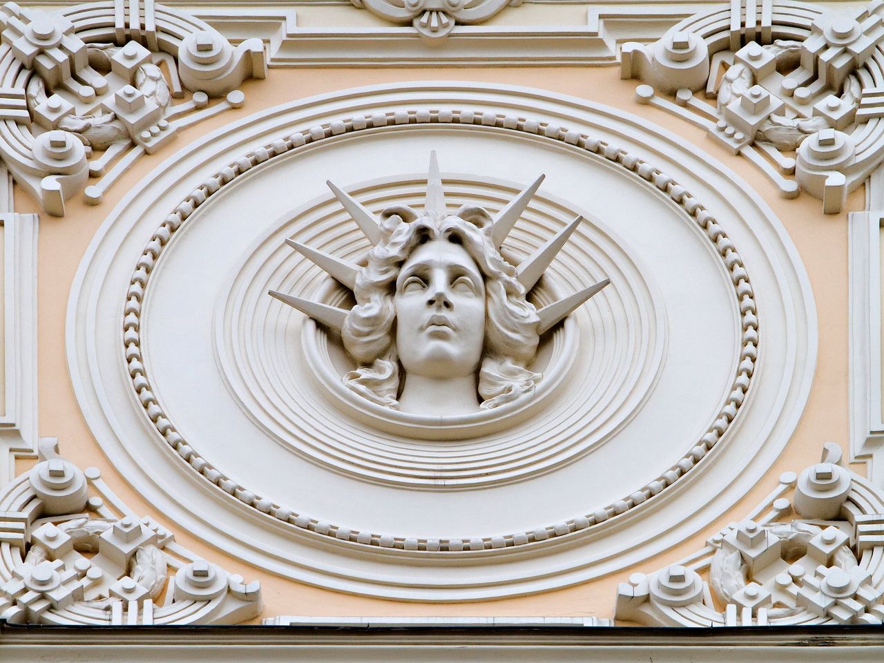 Rygos Art Nouveau fasado detalė: moters veidas ornamentuotame apskritime