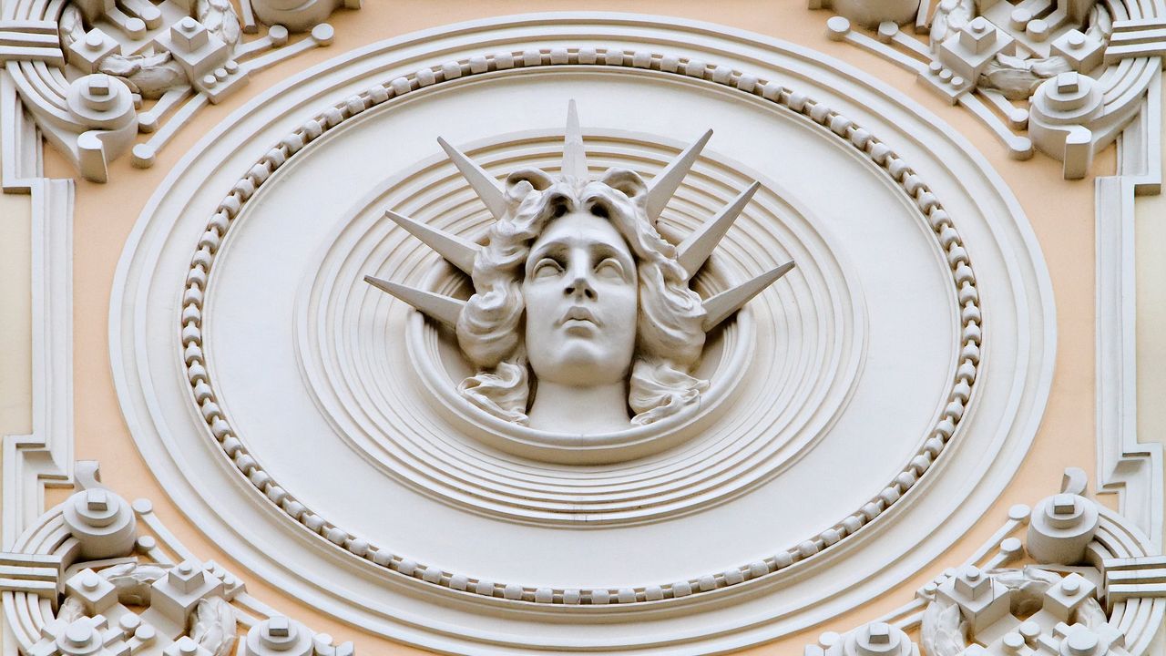 Rygos Art Nouveau fasado detalė: moters veidas ornamentuotame apskritime