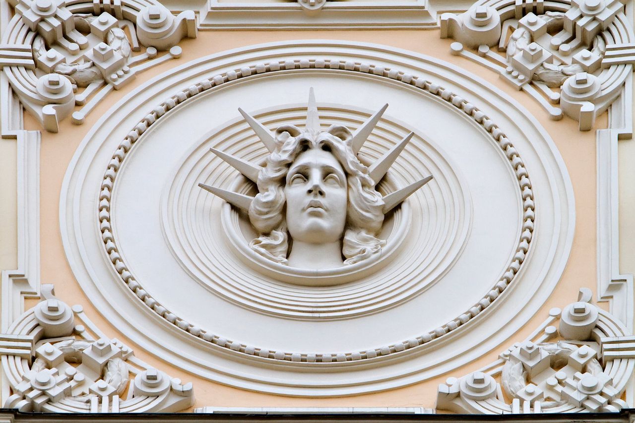 Rygos Art Nouveau fasado detalė: moters veidas ornamentuotame apskritime