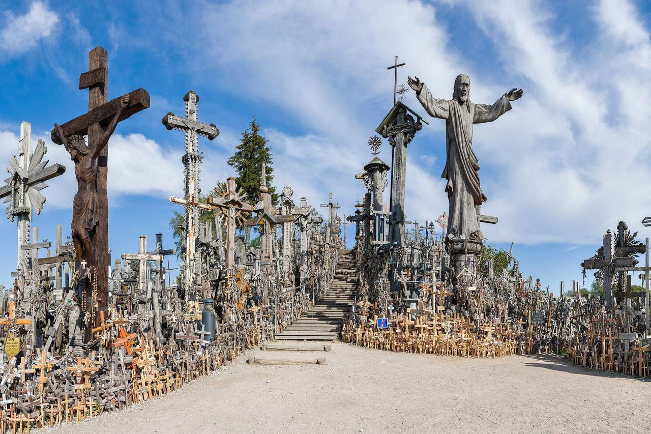 Kryžių kalno takas tarp tūkstančių medinių kryžių ir Kristaus skulptūros mėlyname danguje