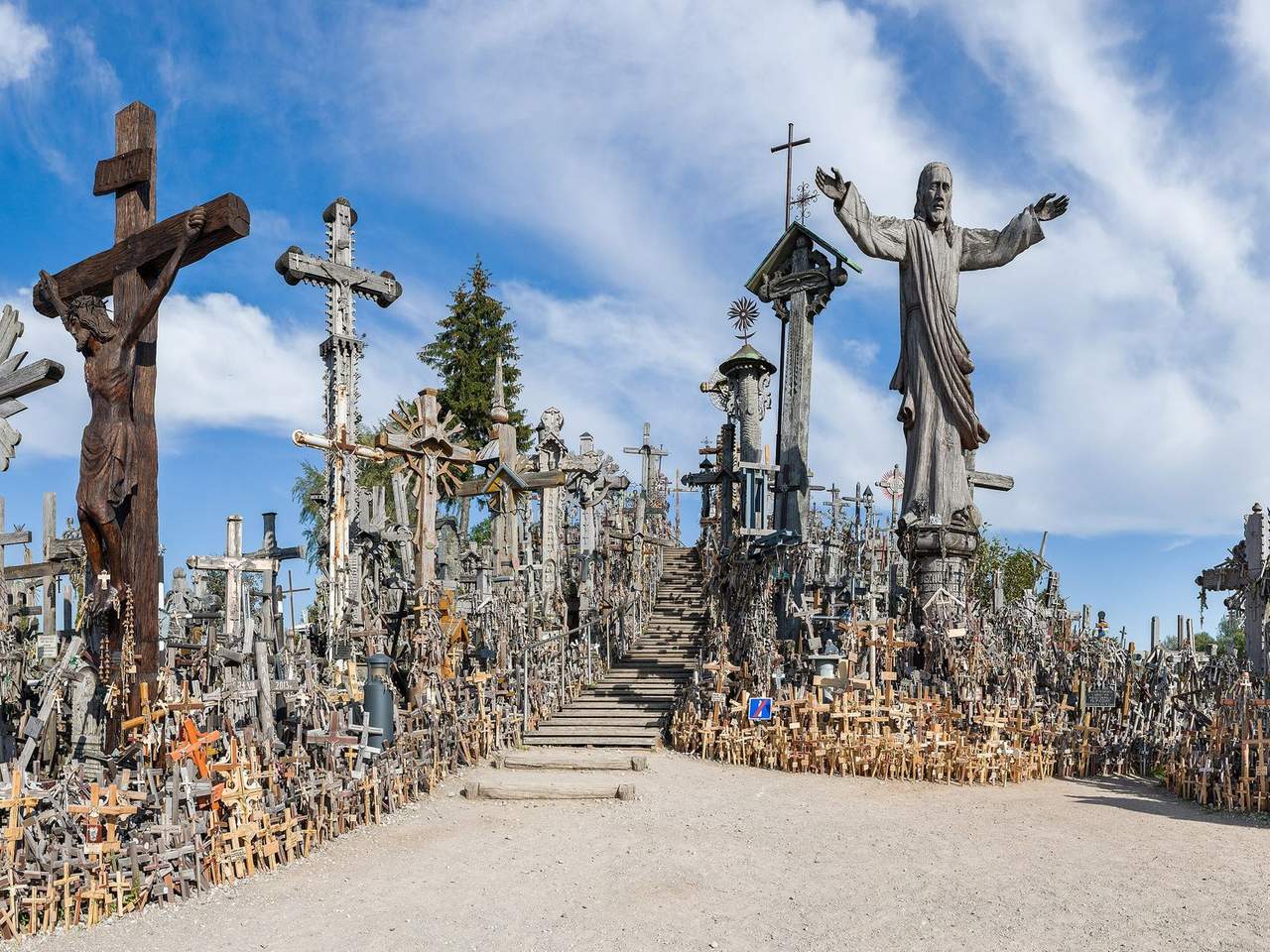 Kryžių kalno takas tarp tūkstančių medinių kryžių ir Kristaus skulptūros mėlyname danguje