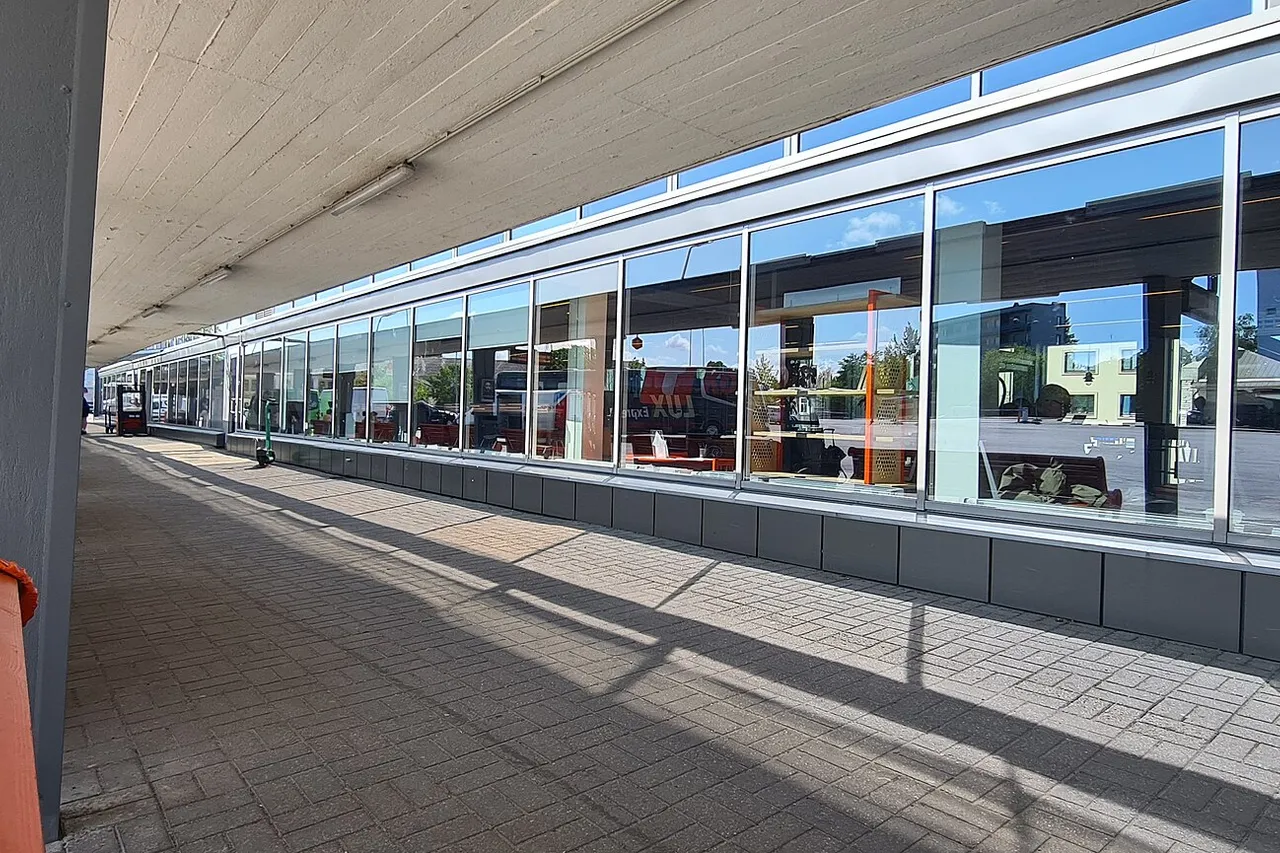 Dengtas Talino autobusų stoties peronas su oranžiniais suolais ir stikliniu laukiamosios fasadu