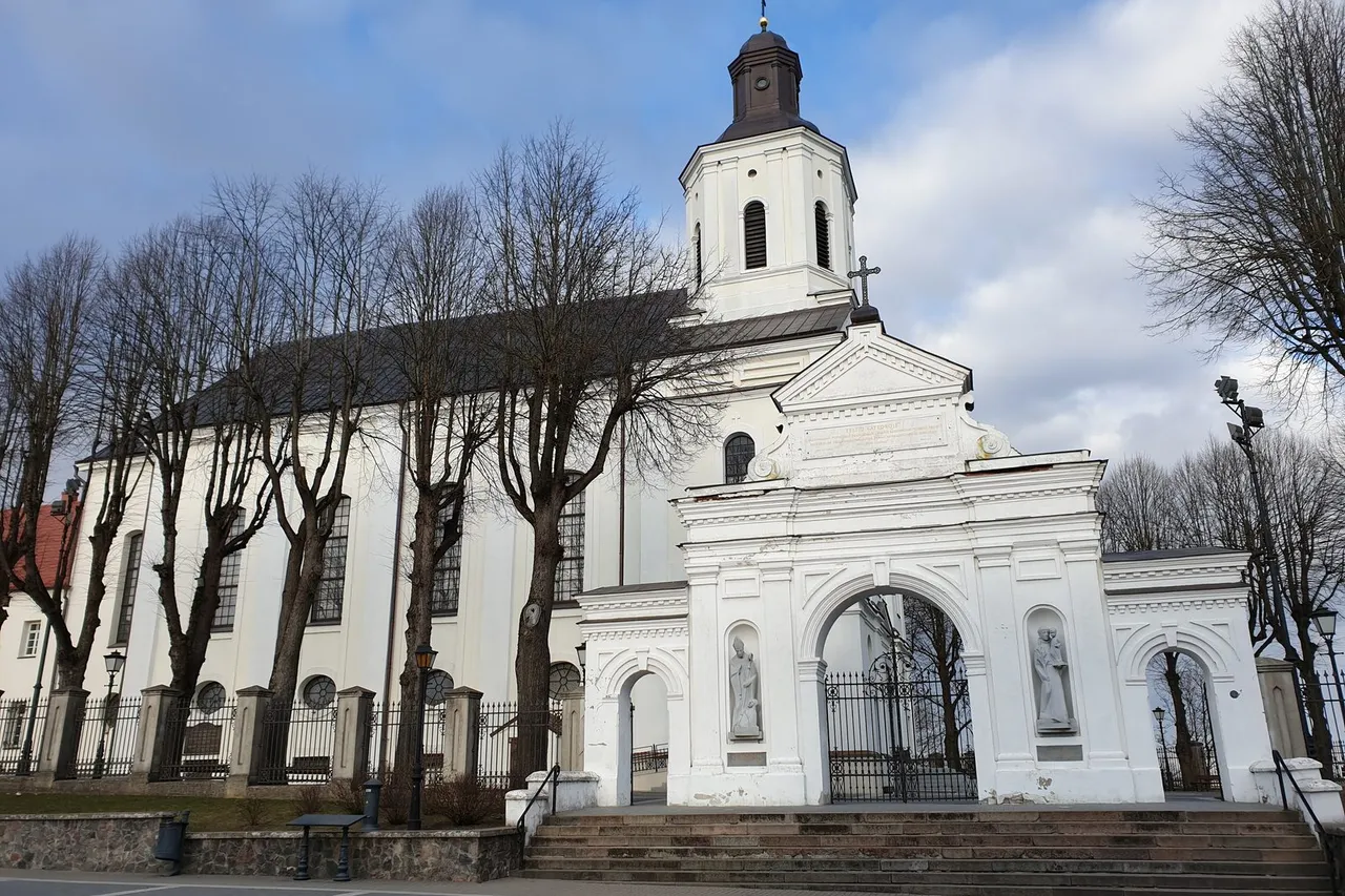 Balta Telšių Šv. Antano Paduviečio katedra su šventoriaus vartais ir plikais medžiais priekyje