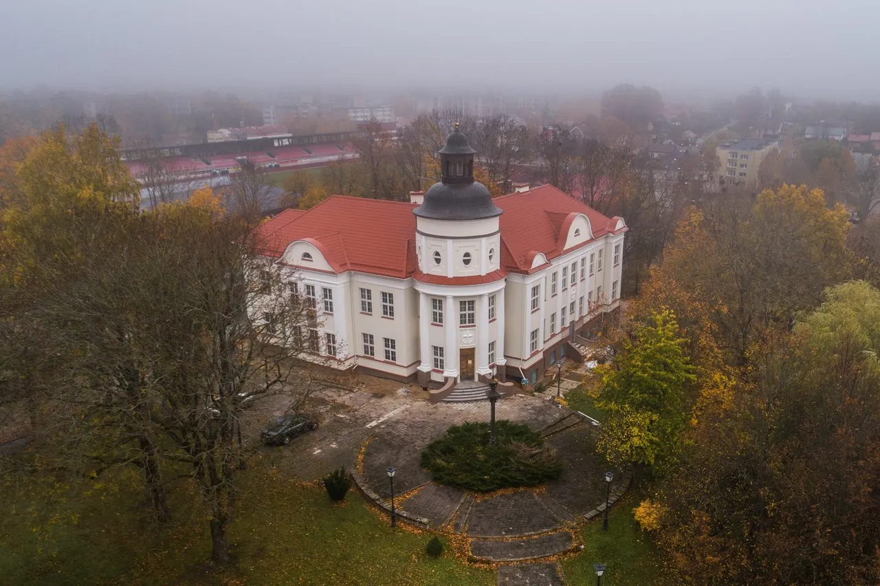 Rudens rūke skendintis baltas Telšių vyskupijos pastatas su raudonu stogu ir kupolu