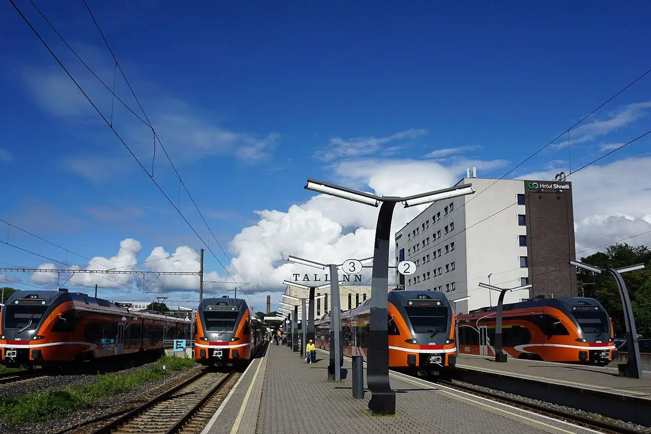 Oranžiniai „Elron“ elektrotraukiniai Talino Baltijos stoties perone, virš jų mėlynas dangus