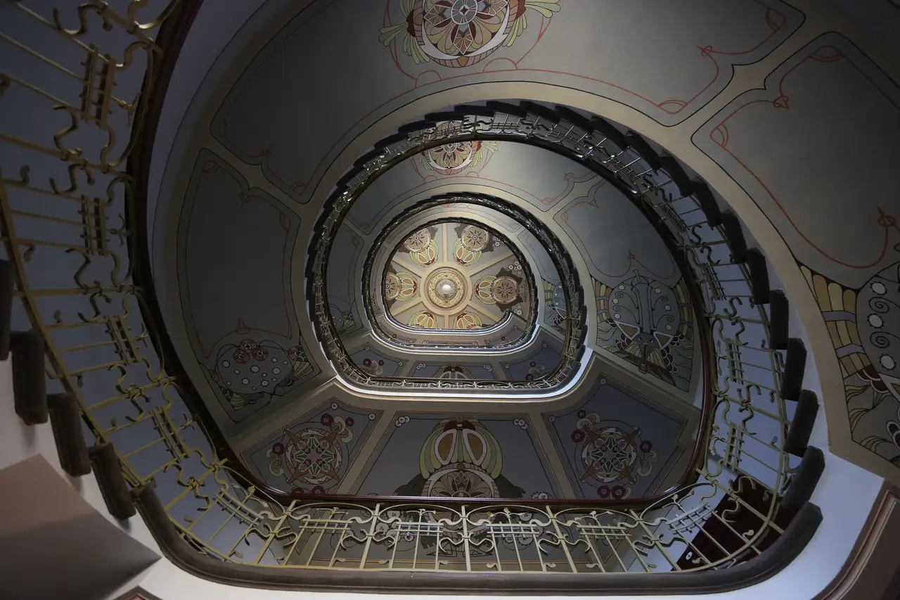 Art Nouveau muziejaus laiptinė Alberto gatvėje 12 Rygoje: išlenkti turėklai ir dažytos lubos