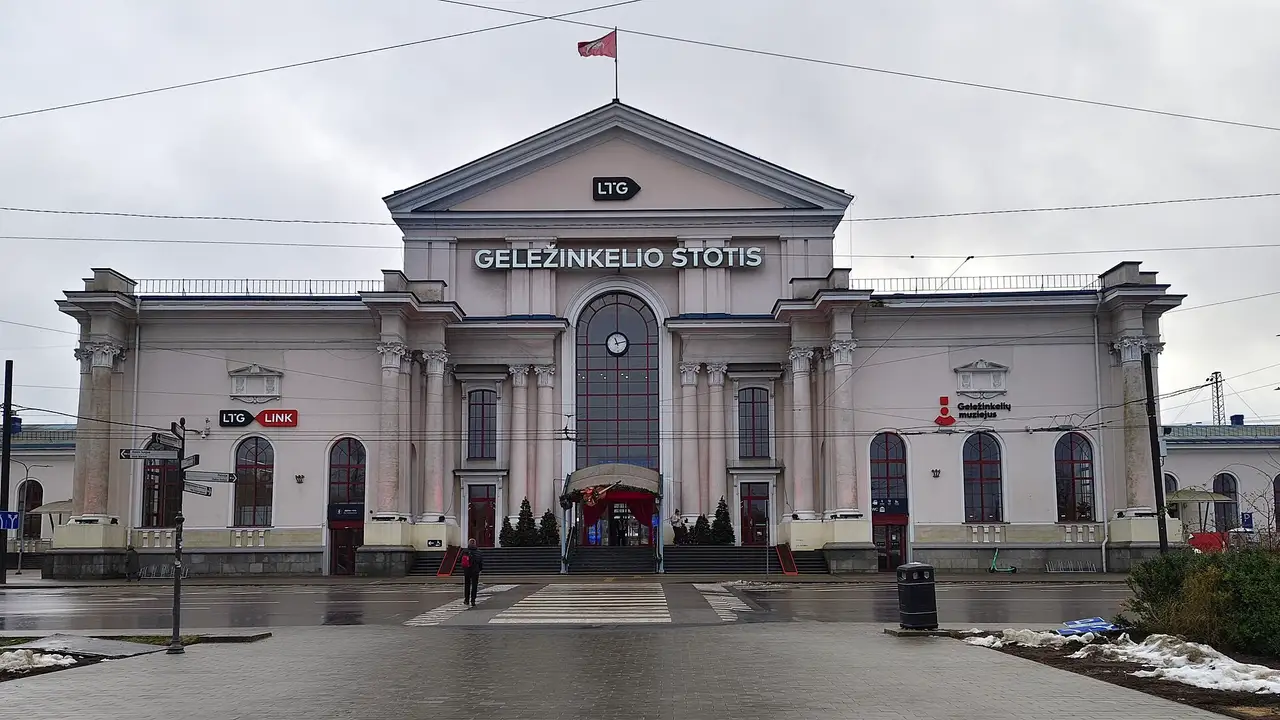 Vilniaus geležinkelio stoties pastatas su kolonomis, laikrodžiu ir užrašu „Geležinkelio stotis“ apsiniaukusią dieną