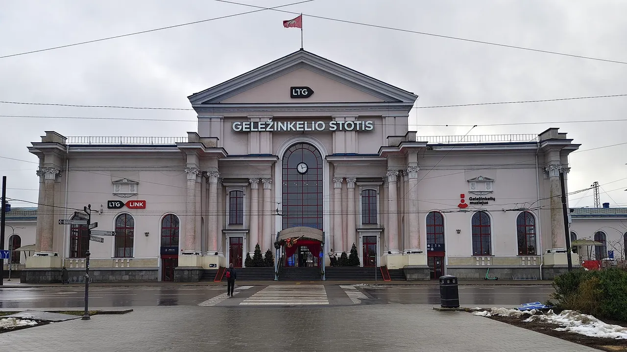 Vilniaus geležinkelio stoties pastatas su kolonomis, laikrodžiu ir užrašu „Geležinkelio stotis“ apsiniaukusią dieną