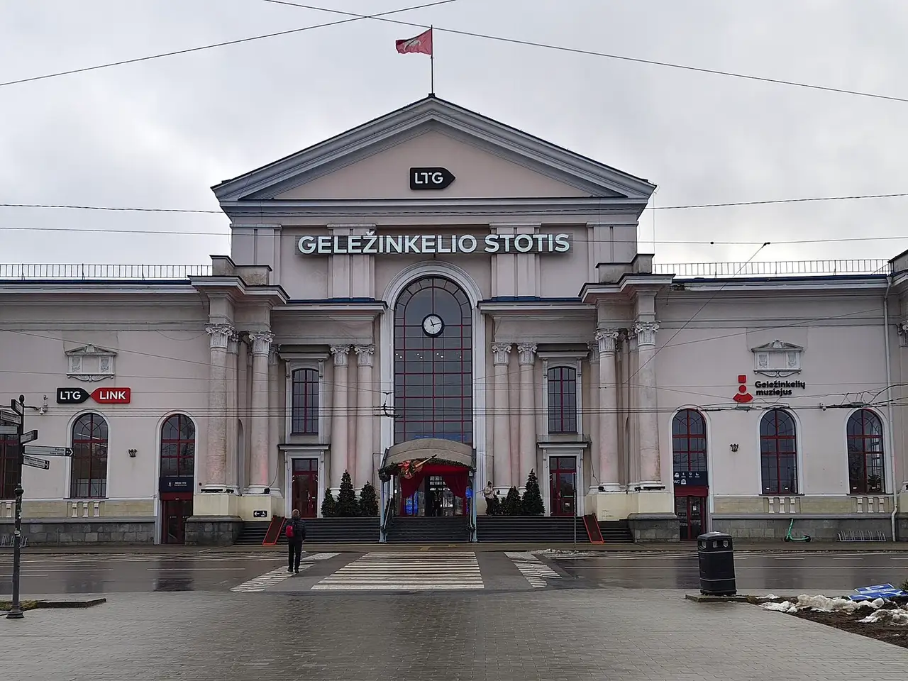 Vilniaus geležinkelio stoties pastatas su kolonomis, laikrodžiu ir užrašu „Geležinkelio stotis“ apsiniaukusią dieną