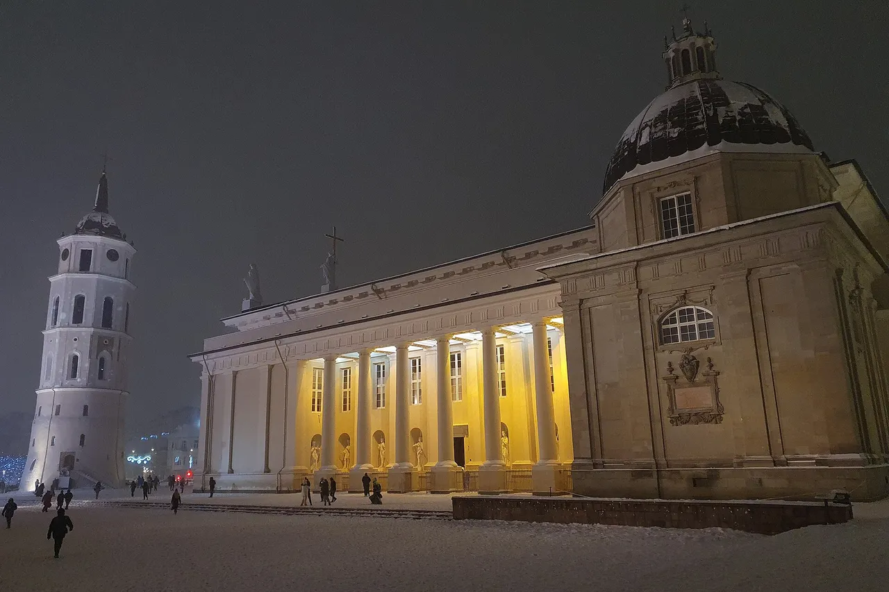 Sniegu padengta Katedros aikštė vakare, apšviesta Vilniaus arkikatedra ir varpinė