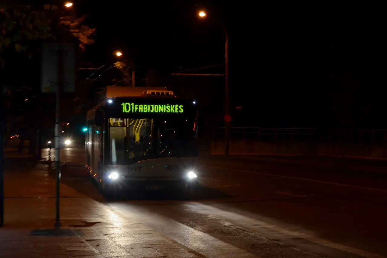 Apšviestas naktinis autobusas Vilniuje važiuoja tamsia gatve