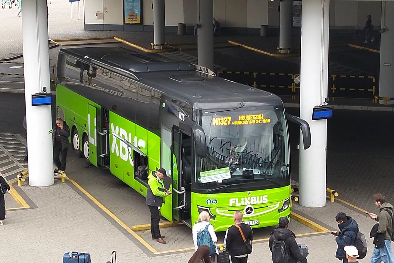 Žalias „FlixBus“ autobusas stovi stotyje po stogine, aplink laukia keleiviai su kuprinėmis