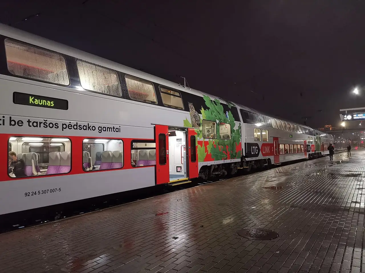 Dviaukštis LTG Link traukinys su užrašu „Kaunas“ stovi šlapiame Vilniaus stoties perone vakare