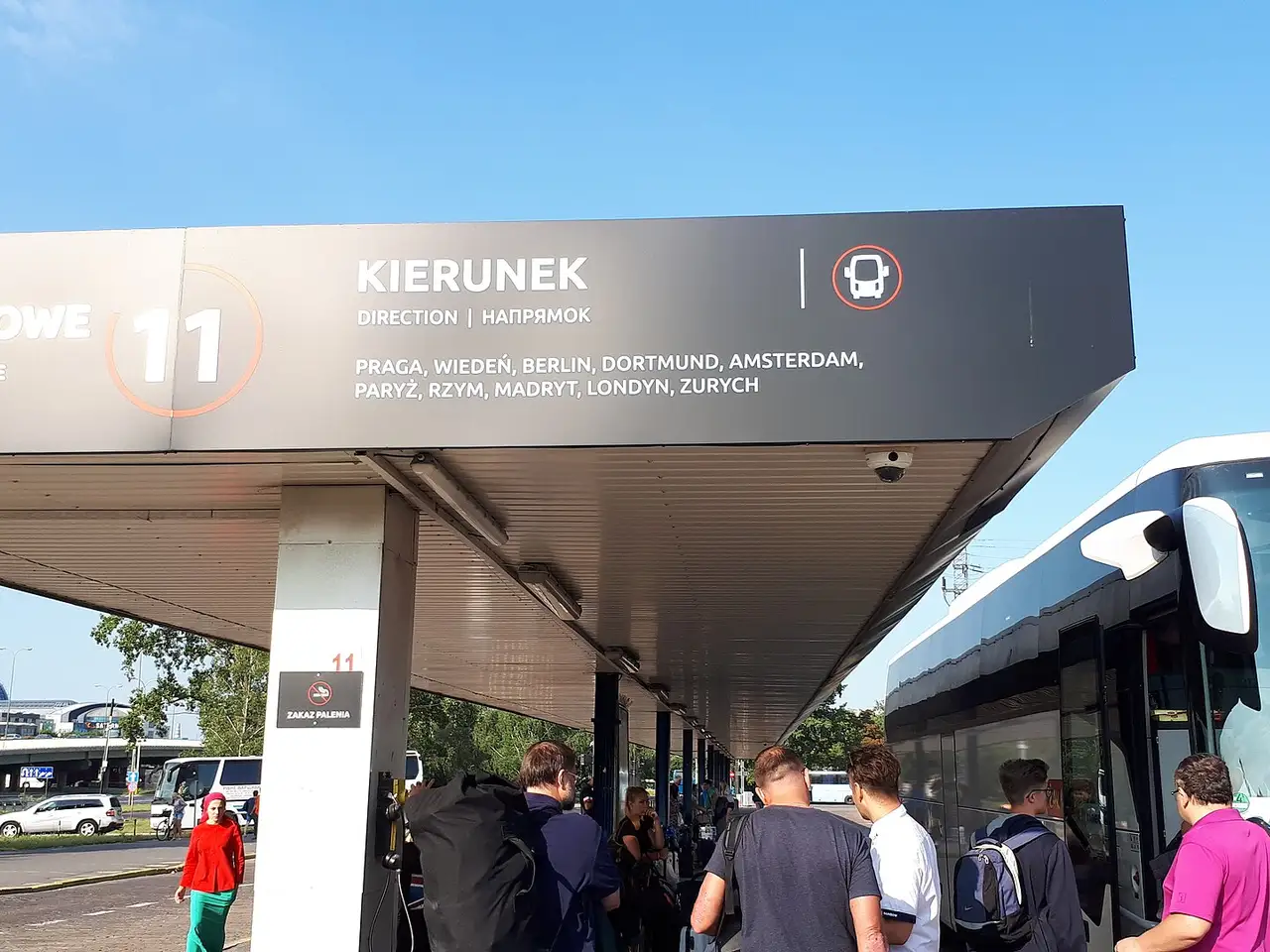Keleiviai laukia autobuso po stoginės nuoroda Varšuvos Zachodnia autobusų stotyje saulėtą rytą
