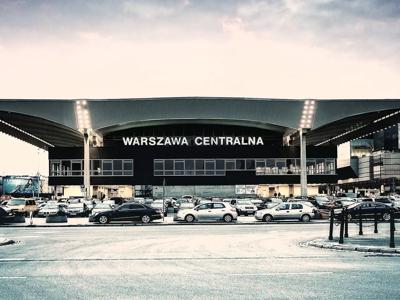 Varšuvos Centrinės stoties pastatas su dideliu stogu ir užrašu Warszawa Centralna prieblandoje